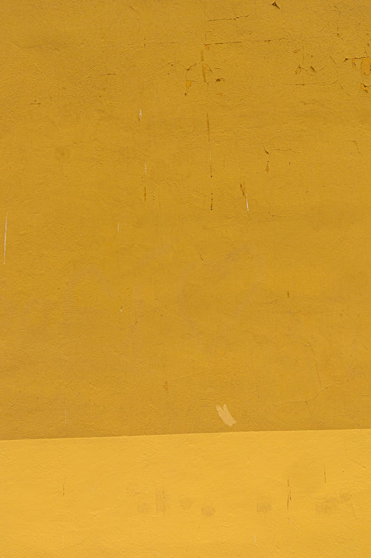 a man riding a skateboard down a street next to a yellow wall